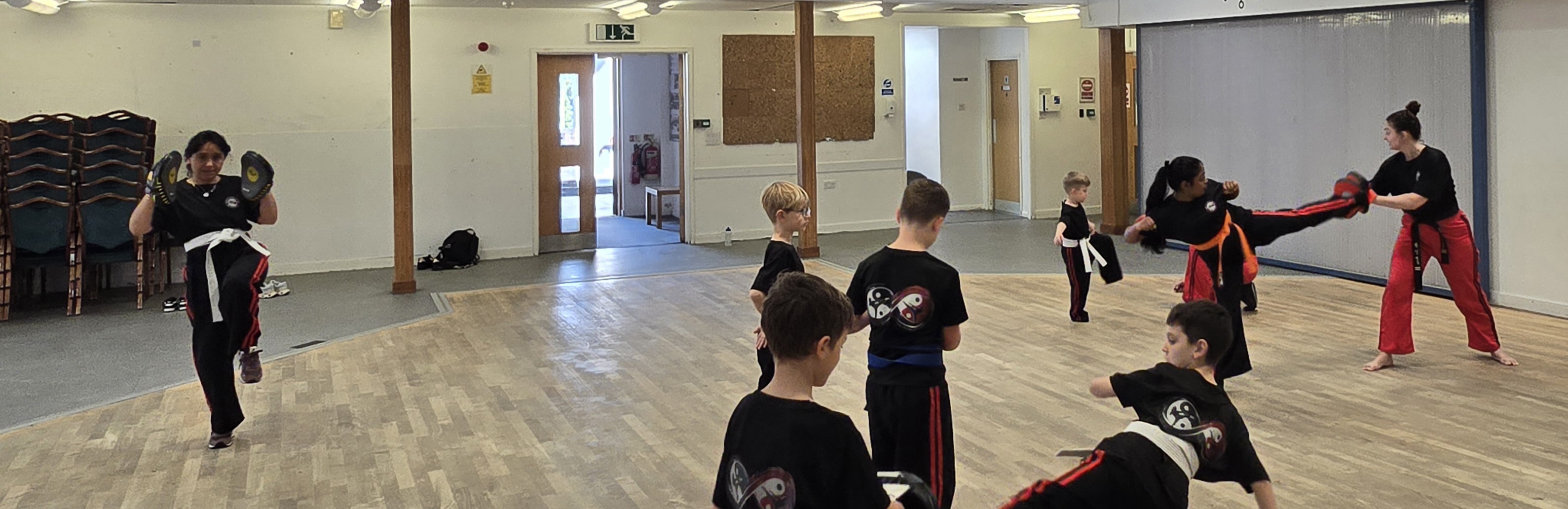 Kids and instructor practising kicks in the main hall