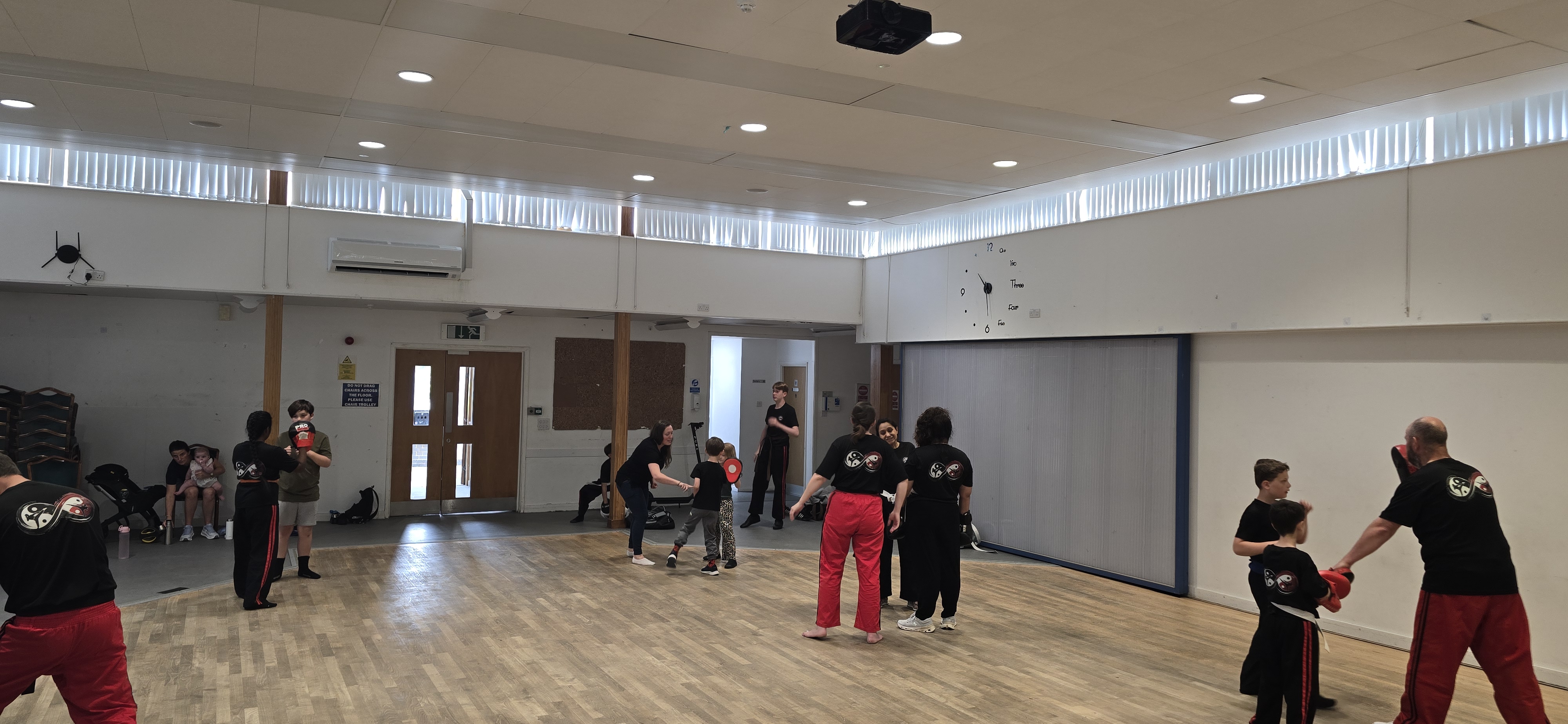 Instructor helping a young student with pad work